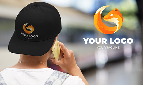 Person in black cap with YOUR LOGO fox emblem, yellow phone, transit station background