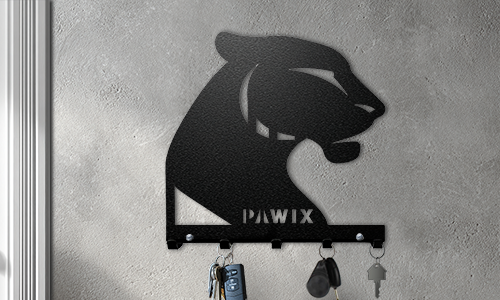 Metal wall key holder with a panther cutout design and personalized name, mounted on a concrete-style wall.