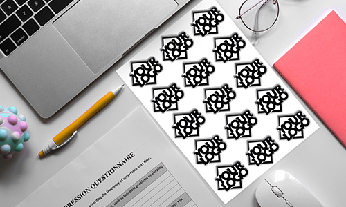 Workspace with laptop, pen, notebook, and “LOVE” sticker sheet — partial depression questionnaire visible.