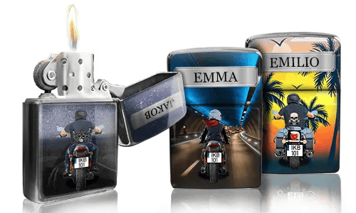 Drei Zippo-Feuerzeuge mit individuellen Designs: eines brennt und zeigt eine nächtliche Autobahnszene, ein anderes zeigt einen Fahrer mit „EMMA“ und das dritte einen Sonnenuntergang mit „EMILIO“.