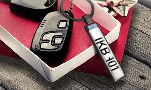 Metal license plate keychain displays engraved numbers beside car keys