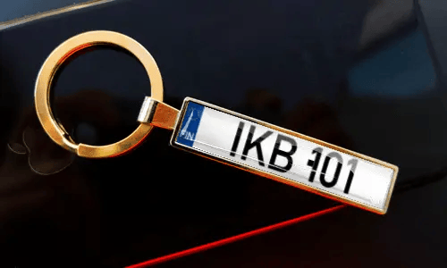 Nummernschild-Schlüsselanhänger an Schlüsseln in der Tasche, mit Auto im Hintergrund