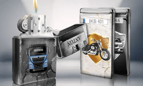 Geöffnetes Metallfeuerzeug mit blauem LKW-Design, Flamme brennt. Dahinter stehen zwei geschlossene Feuerzeuge mit Motiven: ein Motorrad und ein Auto mit Kennzeichen.