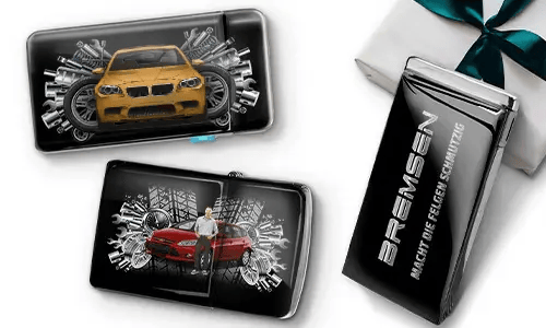 Three sleek black wallets with images of cars and gears, placed near a gift box. 