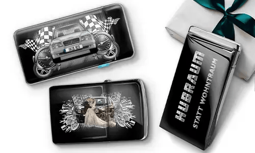 Three black wallets with car-themed designs and checkered flags, set against a white background. One shows a car with wheels, another features a couple, and one has 