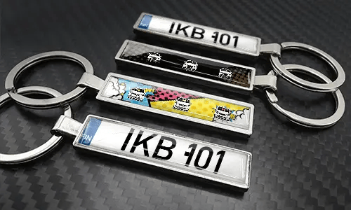 Sleutelhangers in stripstijl met kentekenplaat, gerangschikt op een koolstoftextuur met kleurrijke autographics