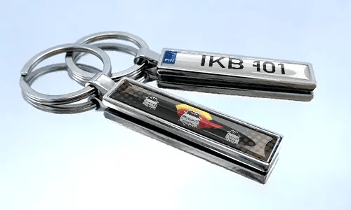 Comic-style license plate keychains with colorful car graphics displayed on a reflective surface