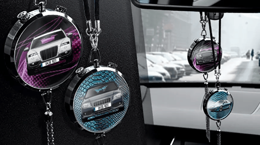Two circular car air fresheners hanging from rearview mirror: left with black car, right with blue car